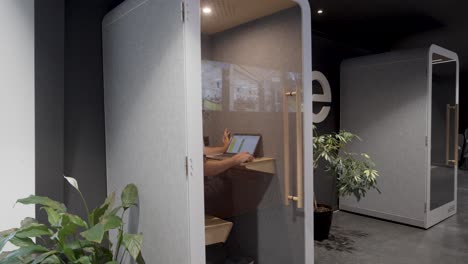 Slow-establishing-shot-of-a-man-working-in-a-single-private-office-pod