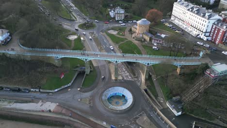 Cinematic-drone-shot-of-a-metallic-blue-foot-over-bridge-with-some-passersby-on-it-during-a-winter-daytime-in-Scarborough-bay,-England