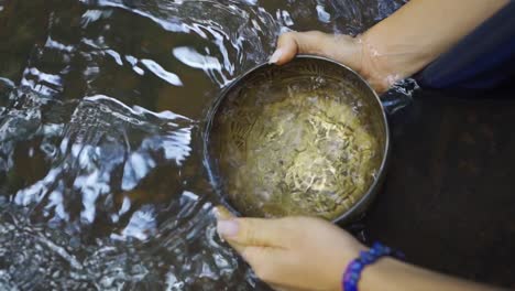 Close-up-shot-of-women-hands-submersing-pot-in-clean-water,-collecting-water