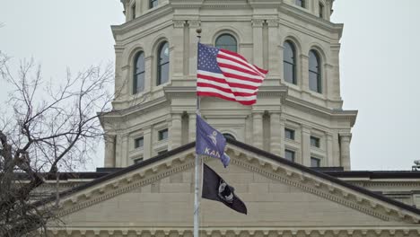 Flags-waving-in-slow-motion-at-the-Kansas-state-capitol-building-in-Topeka,-Kansas-with-stable-close-up-video