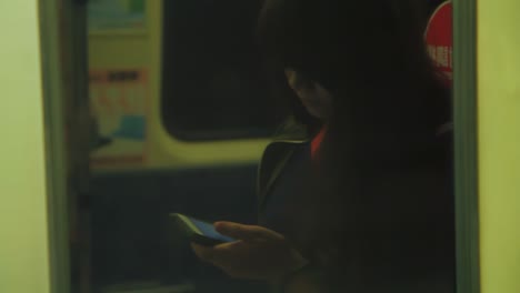 Perspectiva-De-Reflexión-Abstracta-Sobre-Una-Mujer-Asiática-Mirando-Su-Teléfono-En-El-Metro-O-En-El-Tren.
