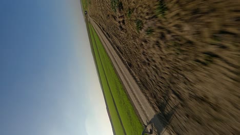 Vertical-format:-Motor-paraglider-skims-rural-dirt-road-ground