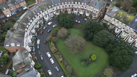 Parallax-drone-shot-of-rows-of-vintage-apartments-surrounding-a-ground-with-trees-during-a-cloudy-day-in-Scarborough-Bay-in-England