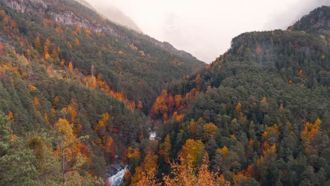 Nahaufnahme-Von-Wasserfall-Und-Bäumen-Im-Ordesa-Nationalpark-Tal-An-Einem-Bewölkten,-Regnerischen-Und-Nebligen-Wintermorgen.-Zeitraffer-Von-Wolken,-Die-In-Der-Herbstsaison-über-Berggipfel-Rollen