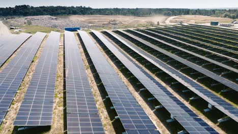 Wide-shot-of-solar-panels-at-low-altitude,-reflections-of-the-sun-on-the-panels-with-dynamic-movement-against-a-background-of-blue-sky