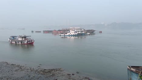 Toma-De-Gran-Angular-De-Un-Ferry-Navegando-Por-El-Río-Hoogly-Y-Un-Barco-Parado-Al-Fondo-Durante-La-Puesta-De-Sol-En-Kolkata,-India