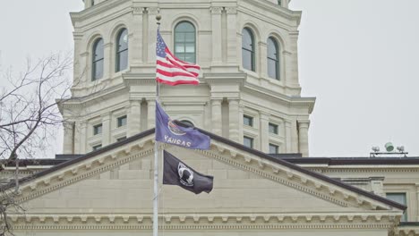 Edificio-Del-Capitolio-Del-Estado-De-Kansas-Con-Banderas-Ondeando-En-Topeka,-Kansas-Con-Banderas-Cercanas-Estables