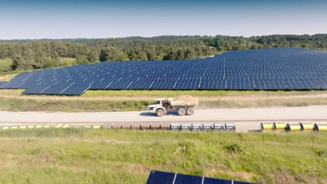 Aerial-view-of-solar-power-station-and-solar-energy-panels,-in-the-background-a-truck-hauls-clay
