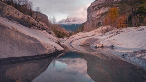 Small-lake-reflection-in-Ordesa-National-park-Mondarruego-mountain-catching-last-sunrays-during-sunset-timelapse-in-fall-autumn-season