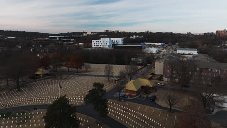Flyover-aerial-of-National-Cemetery,-graves-around-American-flag-in-Fayetteville