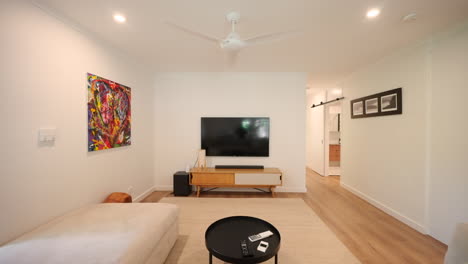 Modernes-Wohnzimmer-Mit-Warmen-Farbtönen,-Weißem-Sofa-Und-Lamellenfenstern,-Die-Natürliches-Licht-Hereinlassen