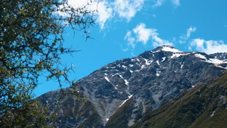 Snow-kissed-peaks:-Mountain-with-patches-of-snow-through-bushes-in-captivating-stock-footage