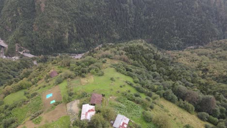 Drone-view-of-several-houses-and-tea-gardens-built-on-the-valley-slope