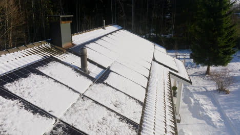 Aerial-view-of-the-sun-melting-a-snowy-photovoltaic-system-on-a-house,-winter-day