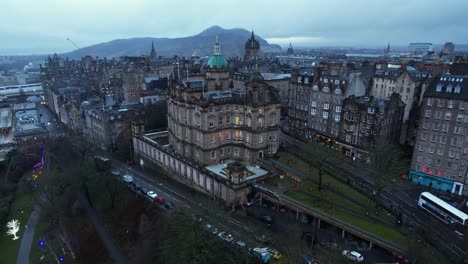 Old-buildings-in-Edinburgh,-with-Holyrood-Park-in-the-background,-4K-Aerial-view