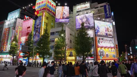 Zeitlupenschwenk-In-Der-Nacht,-Während-Menschen-Die-Straße-In-Richtung-Anime--Und-Otaku-Zentrum-überqueren