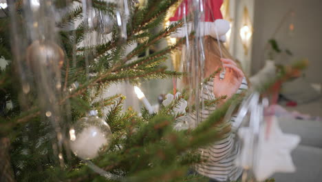 La-Niña-Está-Ayudando-A-Decorar-El-árbol-De-Navidad.