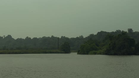 Ruhiger-Fluss,-Der-Durch-Eine-üppige-Grüne-Landschaft-Fließt,-Ein-Hauch-Von-Nebel,-Ruhig-Und-Unberührt-Vom-Städtischen-Leben
