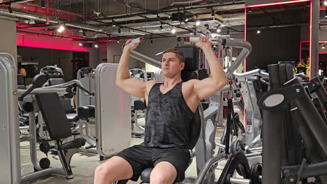 Fit-Man-Trains-Shoulders-Doing-Shoulder-Press-Exercise-in-Machine-at-Modern-Gym