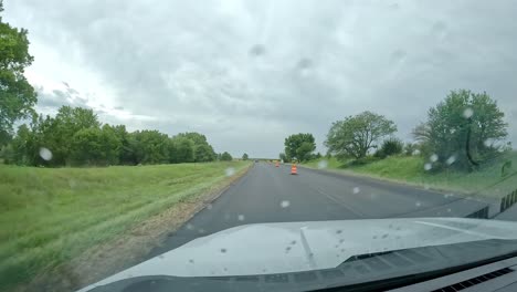 POV--driving-thru-a-construction-zone-on-an-expressway-thru-the-Midwest-countryside-on-a-cloudy,-rainy-day