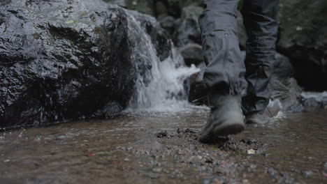 Low-POV-of-stream-in-nature,-feet-going-through-water-and-climbing-on-rock