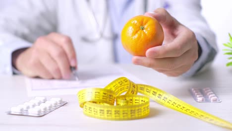 Doctor-holding-a-tangerine-and-talking-about-healthy-eating-behavior-and-benefits,-Close-up