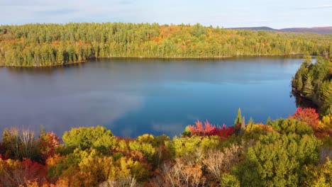 Ein-Ruhiger-See,-Umgeben-Von-Buntem-Herbstlaub-Unter-Einem-Klaren-Himmel,-Der-Die-Lebendigen-Farben-Der-Natur-Widerspiegelt