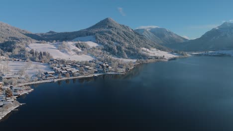 Lake-Schliersee-with-white-snow-winter-landscape,-mountains-and-dark-blue-water