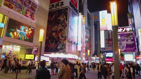 Anime-shopping-center-of-Tokyo,-Pan-from-shop-to-streets-to-reveal-night-life