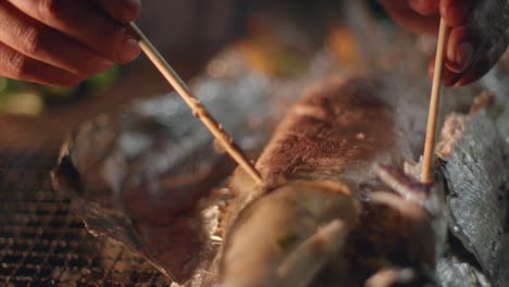 Skin-from-freshly-barbecue-baked-fish-on-foil-removed-using-chopstick-by-hand,-filmed-as-closeup-slow-motion-shot