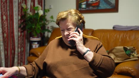 Modern-cheerful-grandmother-talking-to-a-friend-on-cell-phone-at-home