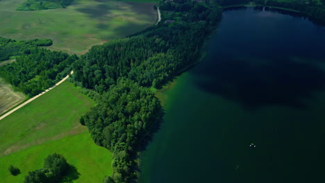 Malerische-Luftaufnahme-Des-Smaragdgrünen-Sees-Mit-Bewachsenem-Ufer-Bei-Sonnenuntergang