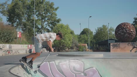 Man-ride-in-skatepark-bowl-with-stunt-scooter-and-perform-slide-tricks