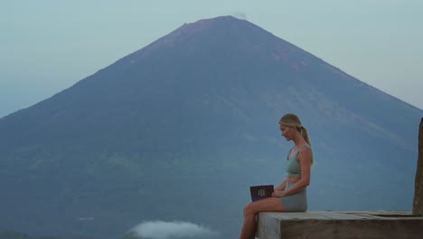 Woman-takes-deep-breath-and-continues-working-on-personal-development-with-journal,-Mount-Agung-in-background