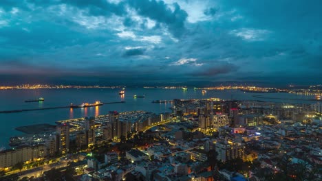 Iconic-cityscape-of-Gibraltar-with-harbor-in-background,-night-lights,-time-lapse