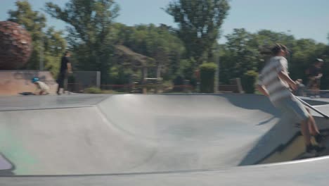 Man-ride-stunt-scooter-at-public-skatepark-bowl-covered-with-graffiti