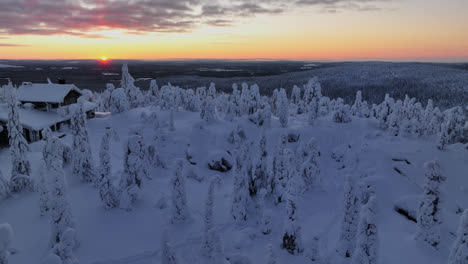 Aerial-tracking-tilt-shot-of-a-house-and-snow-covered-wilderness,-sunset-in-Lapland