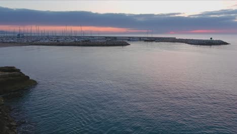 Drone-flying-Roc-de-Sant-Gaieta-coast-with-view-of-Roda-de-Bara-sports-port