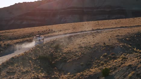 Aerial-View-Of-White-4x4-Truck-Driving-Dusty-Road-Through-The-Bentonite-Hills-In-Utah