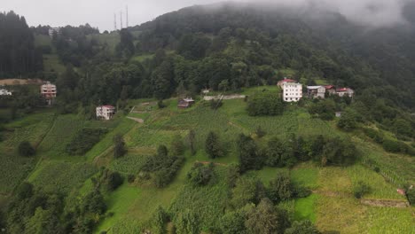Drone-view-of-foggy-mountain-and-rural-settlement,-rainy-plateau-view