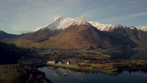 Aerial-panorama-view-of-Isles-of-Glencoe-Hotel-with-och-leven-lake-and-Beautiful-Scottish-highlands-and-snowy-peak-at-sunset,-Scotland