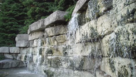 Panning-Close-Up-Shot-of-a-Waterfall-and-Decorative-Garden-Stone-Wall