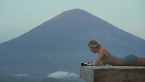 Mujer-Usando-Un-Impresionante-Paisaje-Volcánico-Para-Inspirar-Su-Escritura-En-Un-Diario,-Bali.