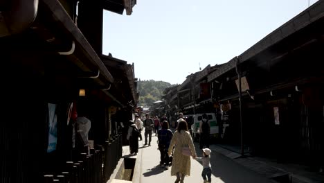 Daytime-capture-of-people-leisurely-walking-along-Sanmachi-Suji,-comprising-three-charming-streets-that-together-form-Hida-Takayama's-renowned-historic-district-in-Japan