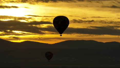 Aerial-telephoto-shot-around-a-hot-air-balloon-with-dramatic-sunrise-background