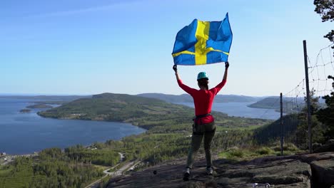 Woman-walks-on-a-mountain-in-slow-motion-with-a-waving-flag-above-her-head