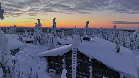 Wooden-cabins-in-middle-of-frosty-forest,-arctic-darkness-in-Lapland---Aerial-view