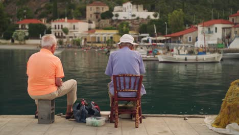 Two-old-men-sit-on-pier-overlooking-Mediterranean-water-at-sunset-fishing-and-enjoying-the-day