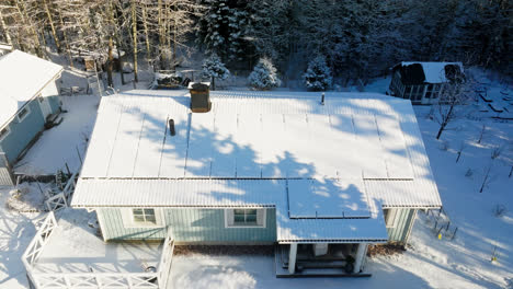 Aerial-view-tilting-away-from-a-detached-house-with-snow-covered-solar-panels