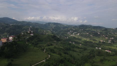 Drone-view-of-the-town-built-on-the-hill,-the-settlement-among-the-greenery